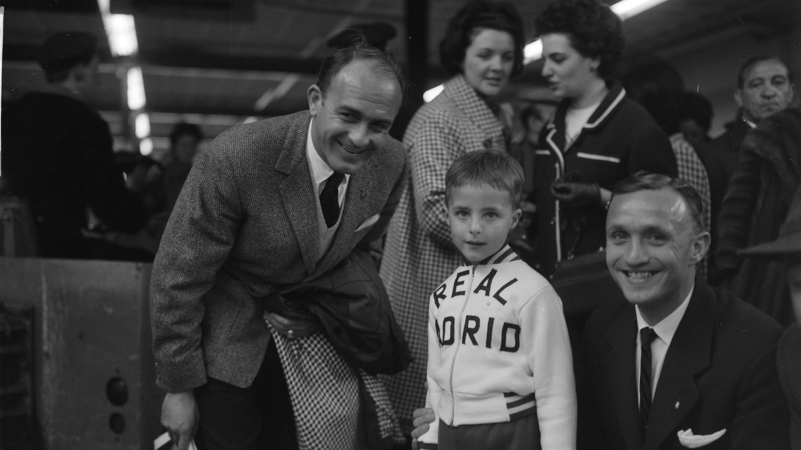 Alfredo Di Stéfano, de saco y corbata, sonríe junto a un niño con un buzo del Real Madrid y a su compañero José Santamaría en el aeropuerto de Schiphol, Ámsterdam, 29 de abril de 1962
